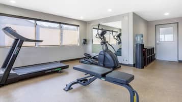 Ein Fitnessraum mit Laufband, Crosstrainer und Bank.