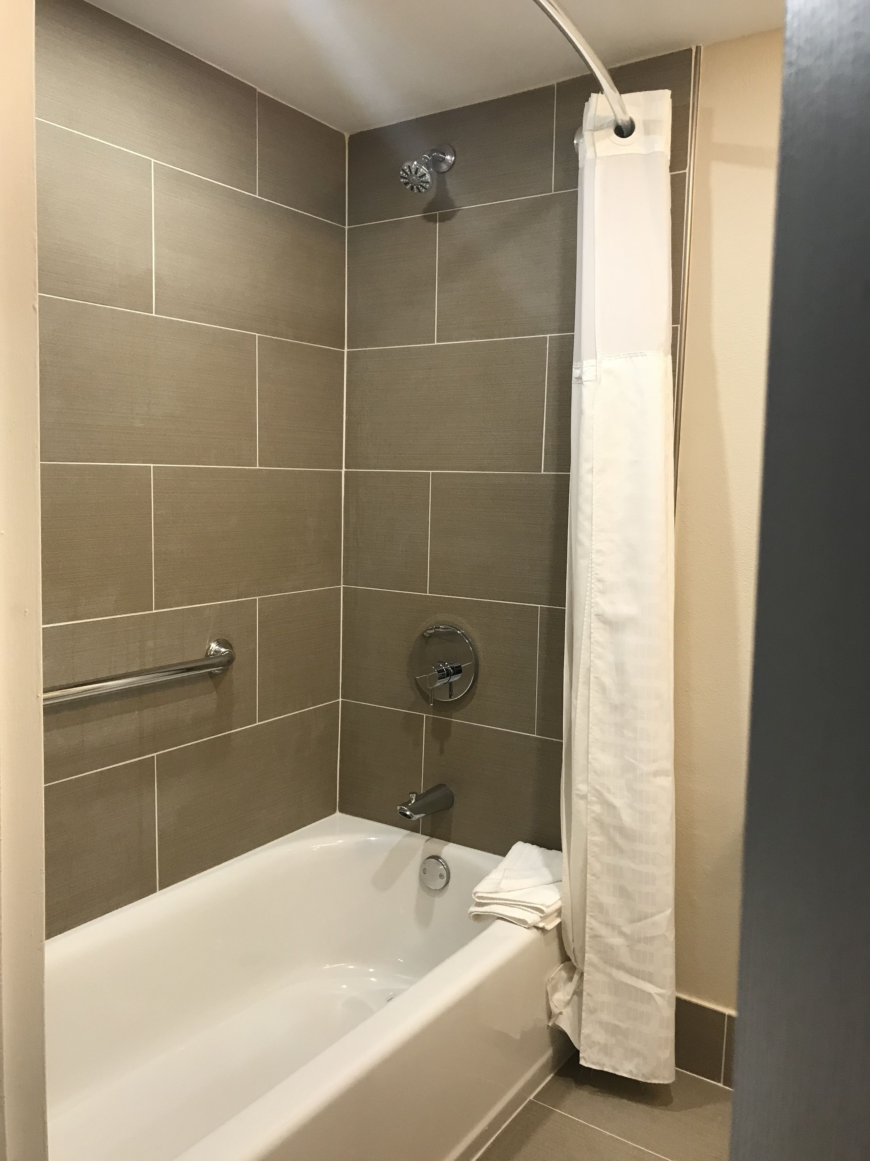 Une salle de bain moderne équipée d’une baignoire, d’une douche et d’une barre d’appui.