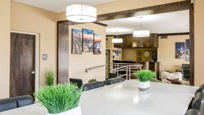 A hotel lobby with a reception desk, seating area, and a view of the cityscape through the windows.