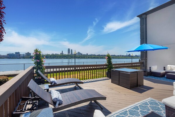 A deck with lounge chairs, a table, and a blue umbrella.