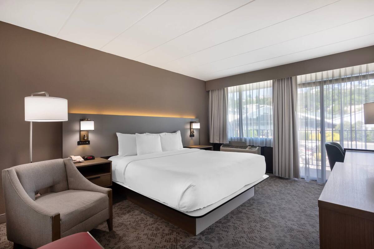 Une chambre d’hôtel comprenant un lit, des tables de chevet, une lampe, une chaise et un bureau.