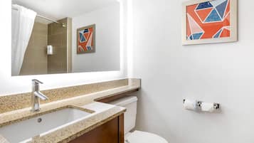 A bathroom with a sink, mirror, toilet, and a framed abstract painting on the wall.