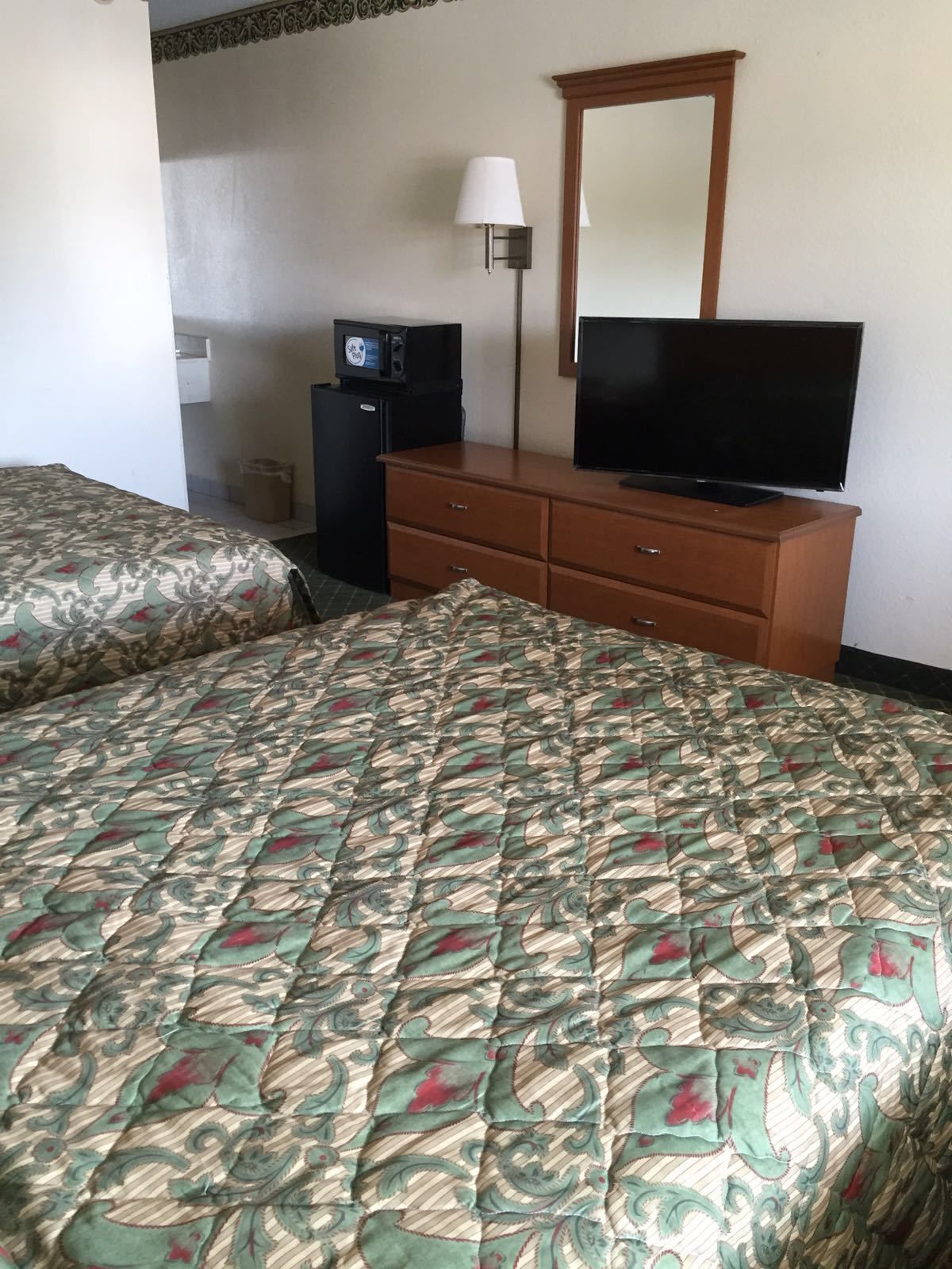 Een hotelkamer met een bed, een kaptafel, een televisie en een magnetron.