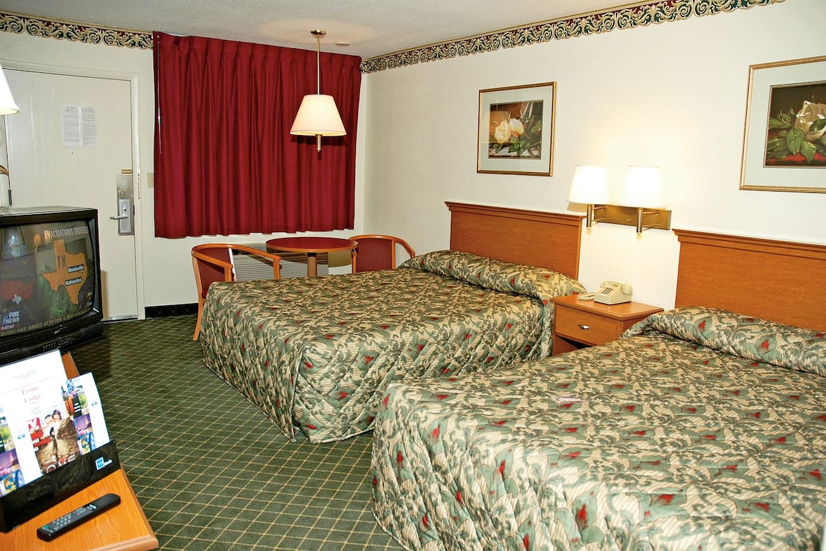 A hotel room with two beds, a television, a desk, and a chair.