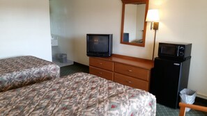 Une chambre d’hôtel avec deux lits, une télévision, un four à micro-ondes, une commode et un miroir.