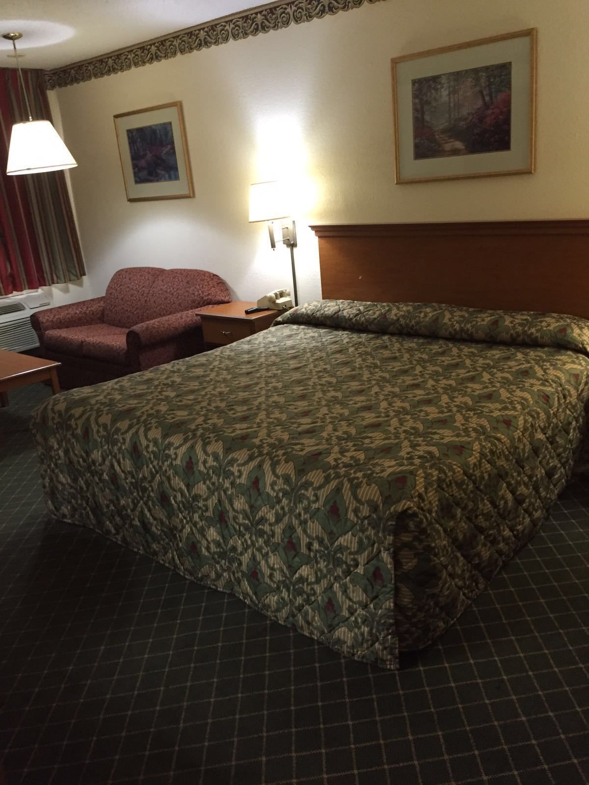 Una habitación de hotel con una cama grande, un sofá, un escritorio y una lámpara.