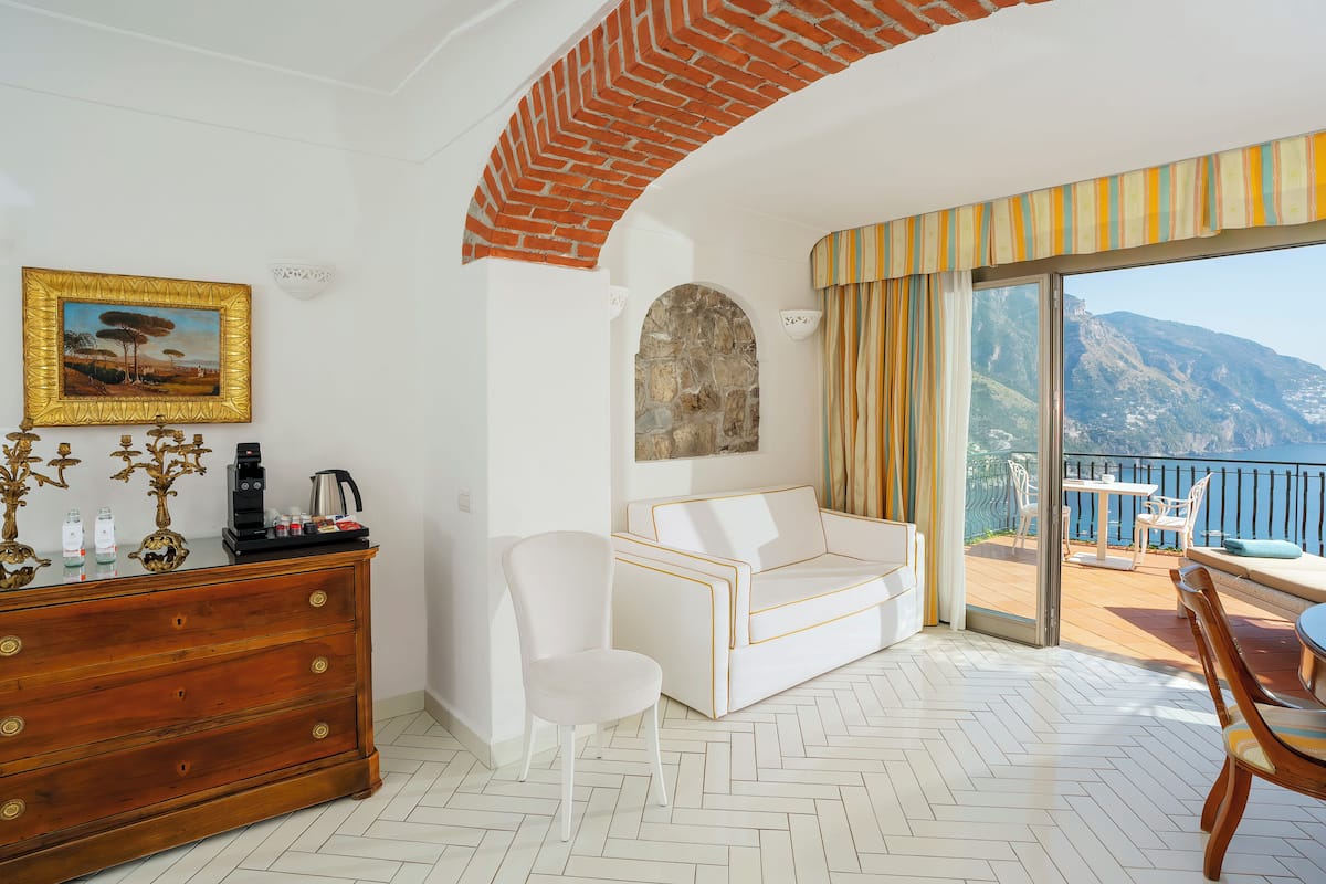 A modern living room with a white sofa, a wooden dresser, and a painting on the wall.