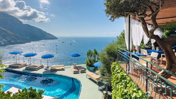 A poolside area with lounge chairs and umbrellas, overlooking a beach and the sea. - Hotel Le Agavi (Positano)