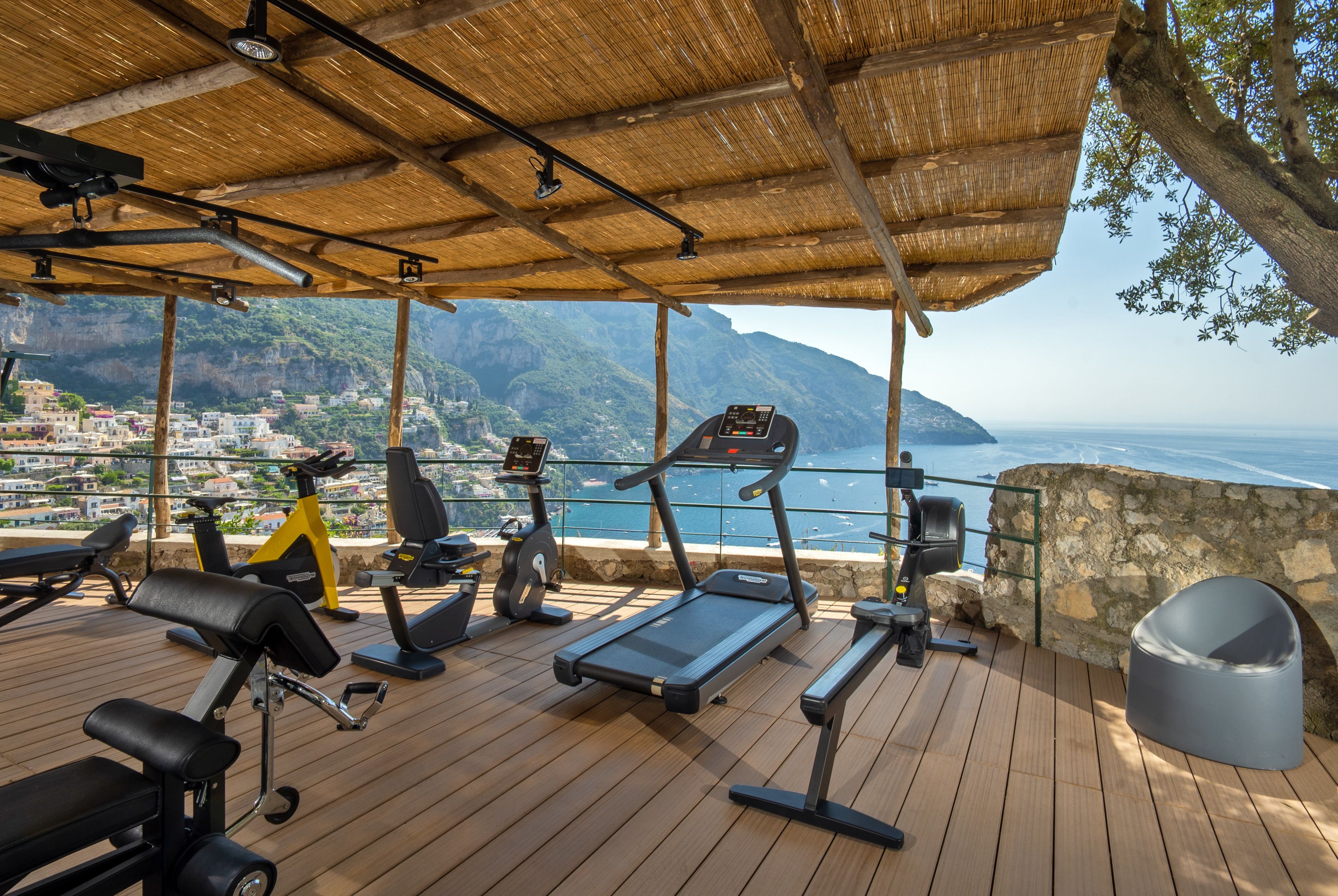 Ein überdachtes Freiluft-Fitnessstudio mit Geräten und einem schönen Blick auf eine Küstenstadt.