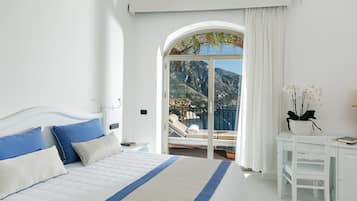 Un dormitorio con cama, mesita de noche, silla, planta en maceta y vistas a un balcón con silla y mesa.