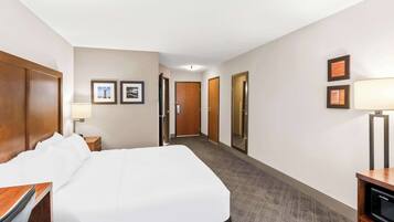 Een hotelkamer met een groot bed, een bureau met lamp, een televisie en ingelijste foto’s aan de muur.