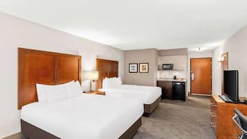 A hotel room with two beds, a desk, a microwave, and a television.