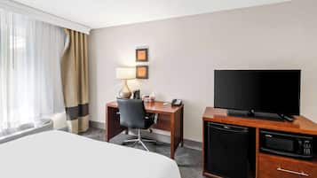 Une chambre d’hôtel équipée d’un lit, d’un bureau avec une chaise, d’une télévision, d’un four à micro-ondes et d’un mini-réfrigérateur.