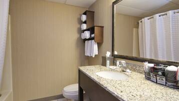 A bathroom with a granite countertop, a sink, a mirror, a towel rack, and a toilet.