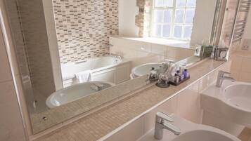 Un baño moderno con un espejo grande, dos lavamanos, una bañera y una ventana que proporciona luz natural.