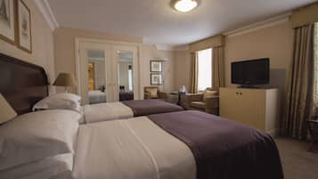 Habitación de hotel con dos camas, televisión, escritorio y una silla.