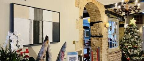 A hotel lobby with a stone archway, a Christmas tree, and a mirror on the wall.