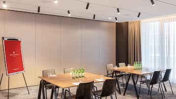 A conference room with a wooden table, six chairs, a red flip chart, and green bottles on the table.