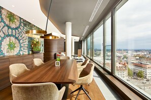 A modern conference room with a large table, comfortable chairs, a decorative wall, and a city view through large windows.
