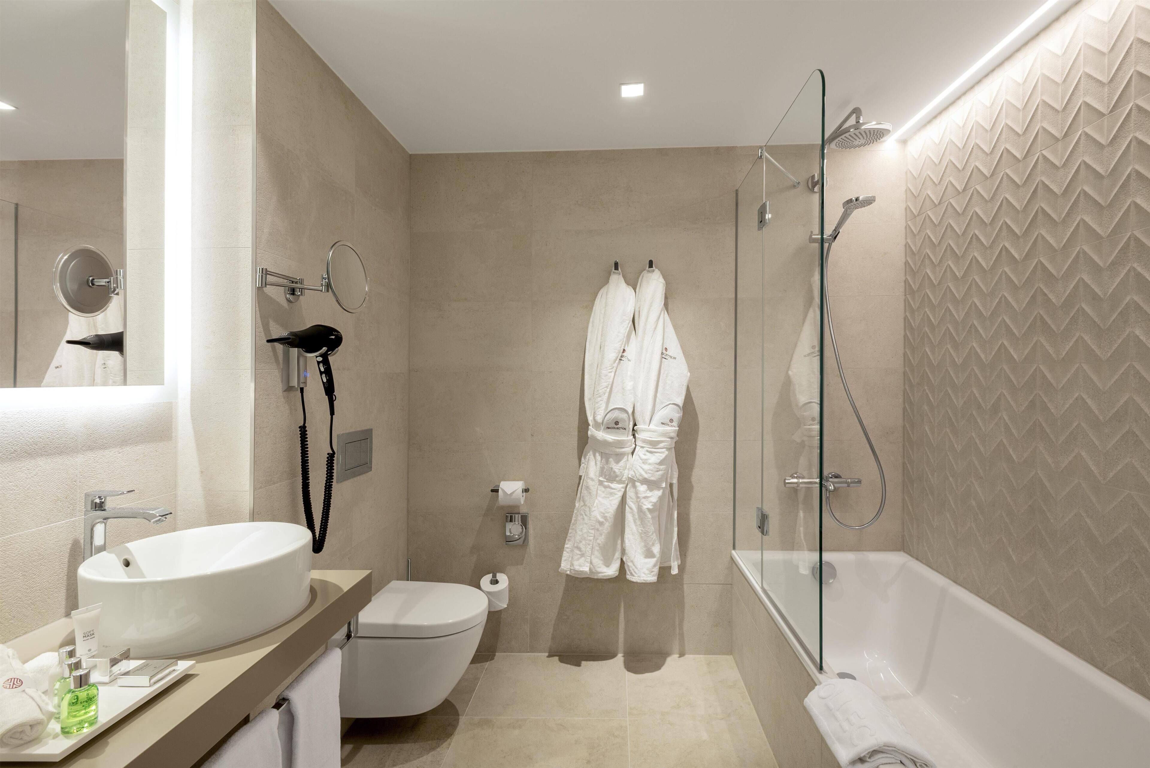 A modern bathroom with a bathtub, a toilet, a sink, and a glass-enclosed shower area.