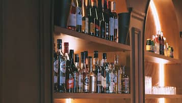 Zona de bar con estantes llenos de botellas de licor y una máquina de café.