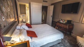 A hotel room with a large bed, a dresser, a television, and a door leading to another room.
