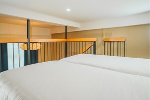 Habitación de hotel con una cama grande, cabecera de madera, escalera y lámpara moderna.