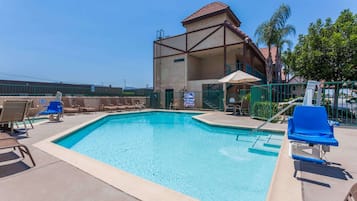 Relax by the pool surrounded by lounge chairs and a balcony overlooking the surrounding area.