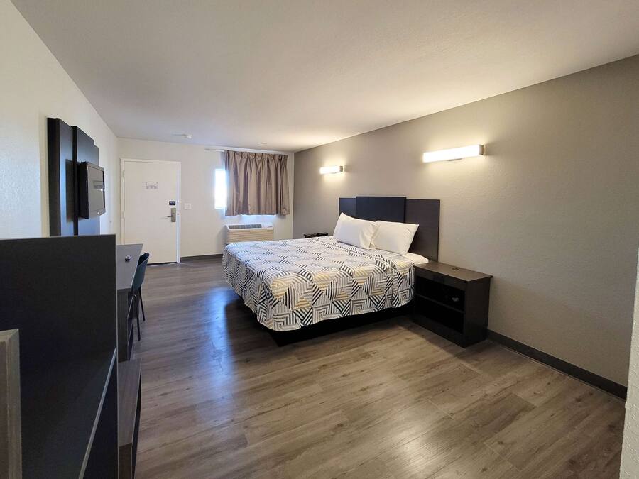 Una habitación de hotel moderna con una cama grande, un escritorio y un televisor.