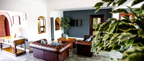 A living room with a stone floor, leather sofas, a wooden coffee table, and a potted plant.