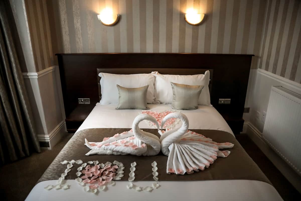 A hotel room with a large bed, two wall-mounted lights, and a headboard.