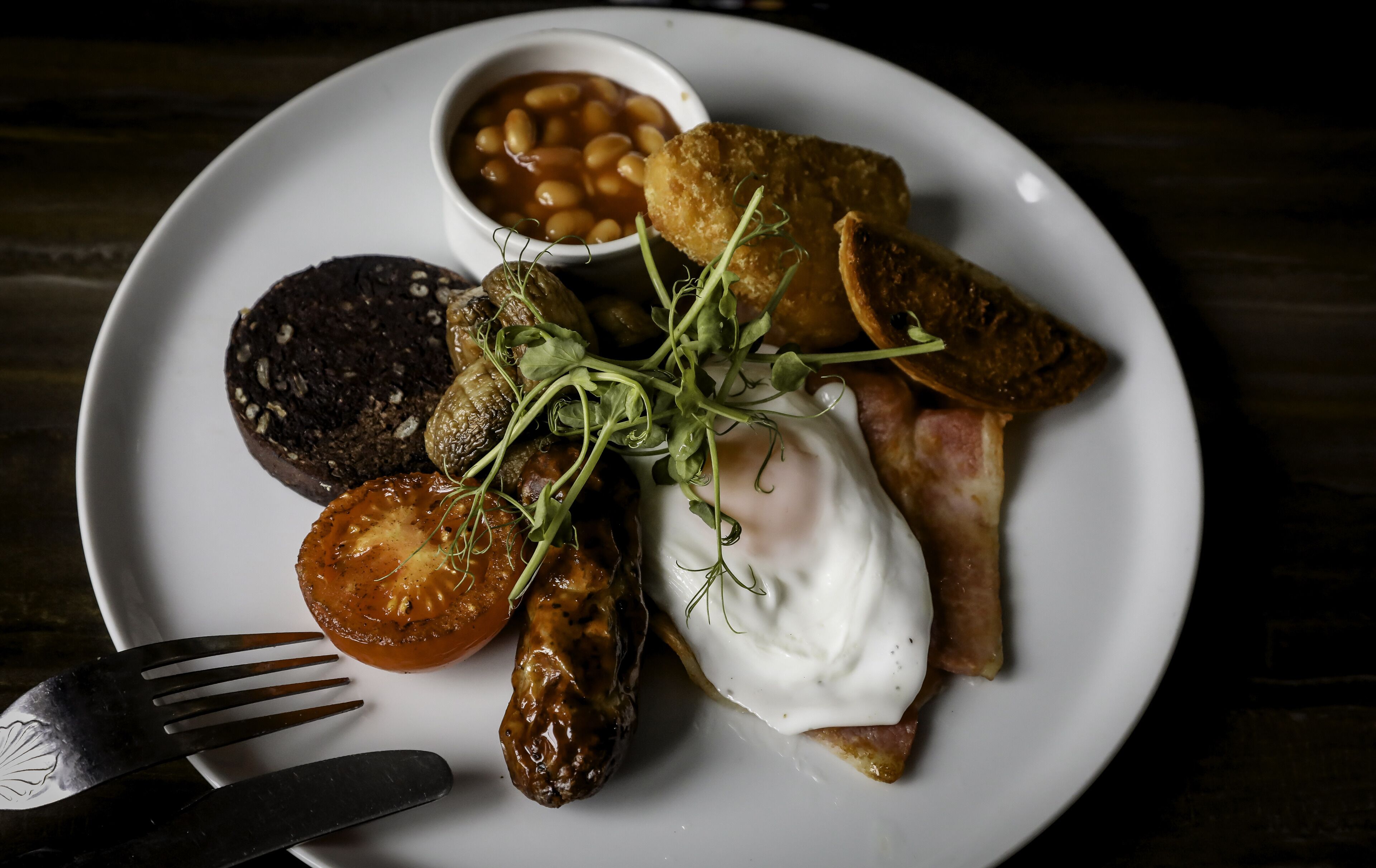 A plate of breakfast food including eggs, sausages, beans, and a slice of toast.