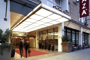 De ingang van Crowne Plaza met een rode loper en plantenpotten.