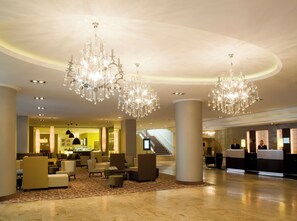 Un hall d’entrée spacieux, agrémenté d’un magnifique lustre, d’un espace salon et d’un comptoir d’accueil.
