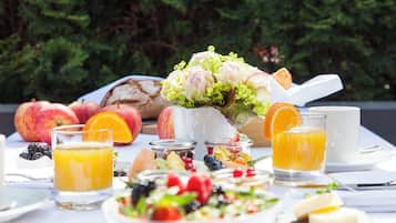 Ein Frühstückstisch mit Früchten, einem Blumenstrauß und Getränken.