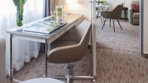 Une chambre d’hôtel équipée d’un bureau, d’une chaise, d’une lampe et offrant une vue sur une autre chambre où se trouvent un lit et une chaise.