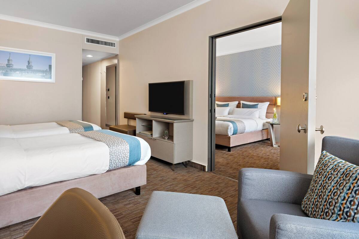Habitación de hotel con una cama grande, un televisor, un escritorio y una silla.