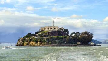 A historic building on a small island surrounded by water, with a lighthouse and a boat in the foreground.