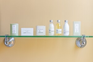 A shelf with various toiletries including a shower cap, bottles of body wash, and a box.