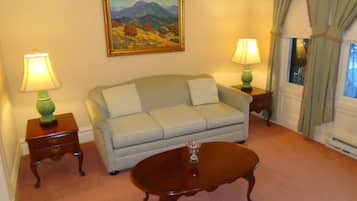 A living room with a sofa, two side tables with lamps, a coffee table, and a painting on the wall.