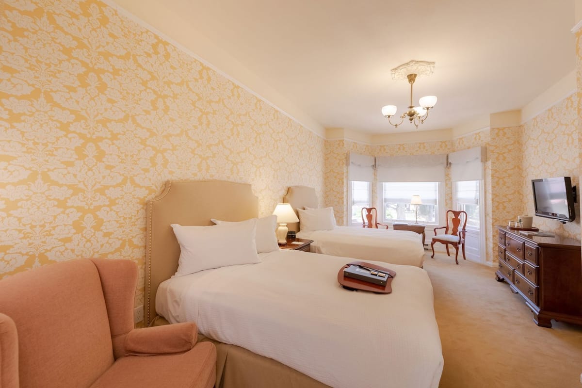 Ein Hotelzimmer mit zwei Betten, einem Fernseher, einem Schreibtisch und einem Stuhl.