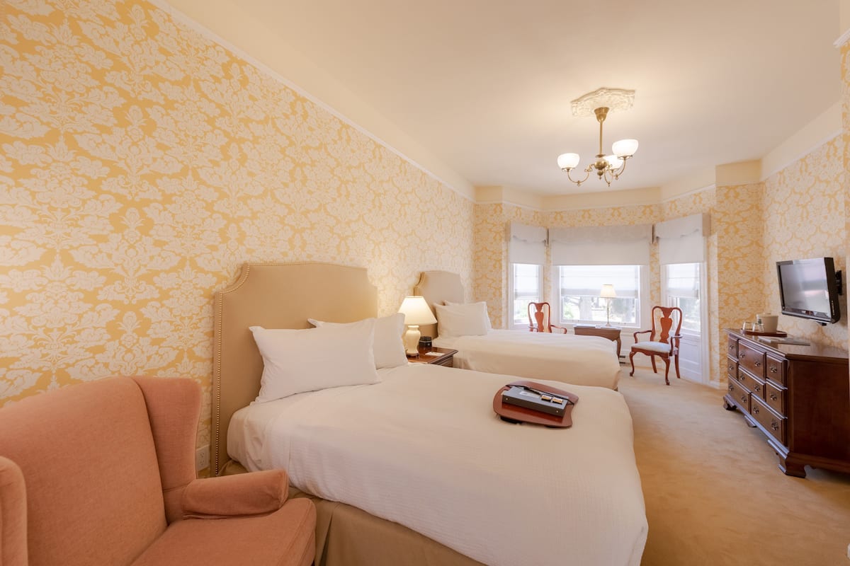 Ein Hotelzimmer mit zwei Betten, einem Fernseher, einem Schminktisch und einem Stuhl.