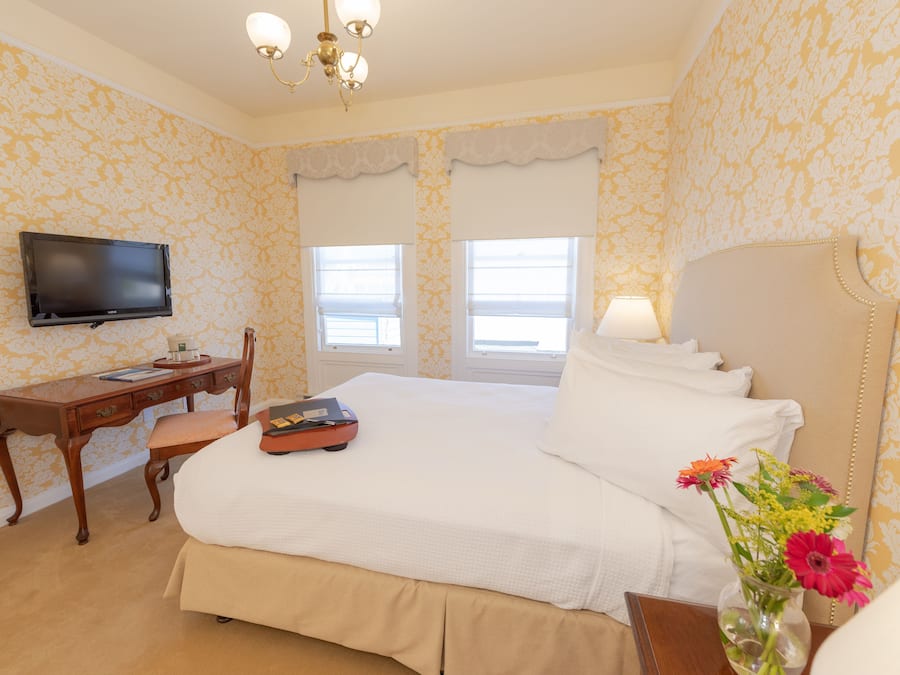 A hotel room with a bed, a desk, a chair, a television, and a window with a view.
