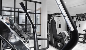 A gym with various exercise equipment, including a treadmill, weight machines, and a cable machine.