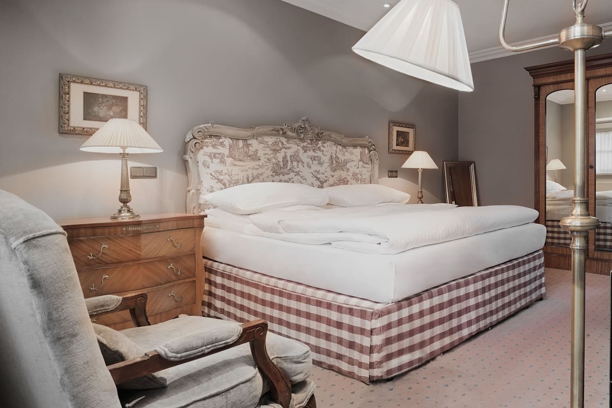 Un dormitorio ordenado con cama, dos lámparas de noche, cómoda y espejo.