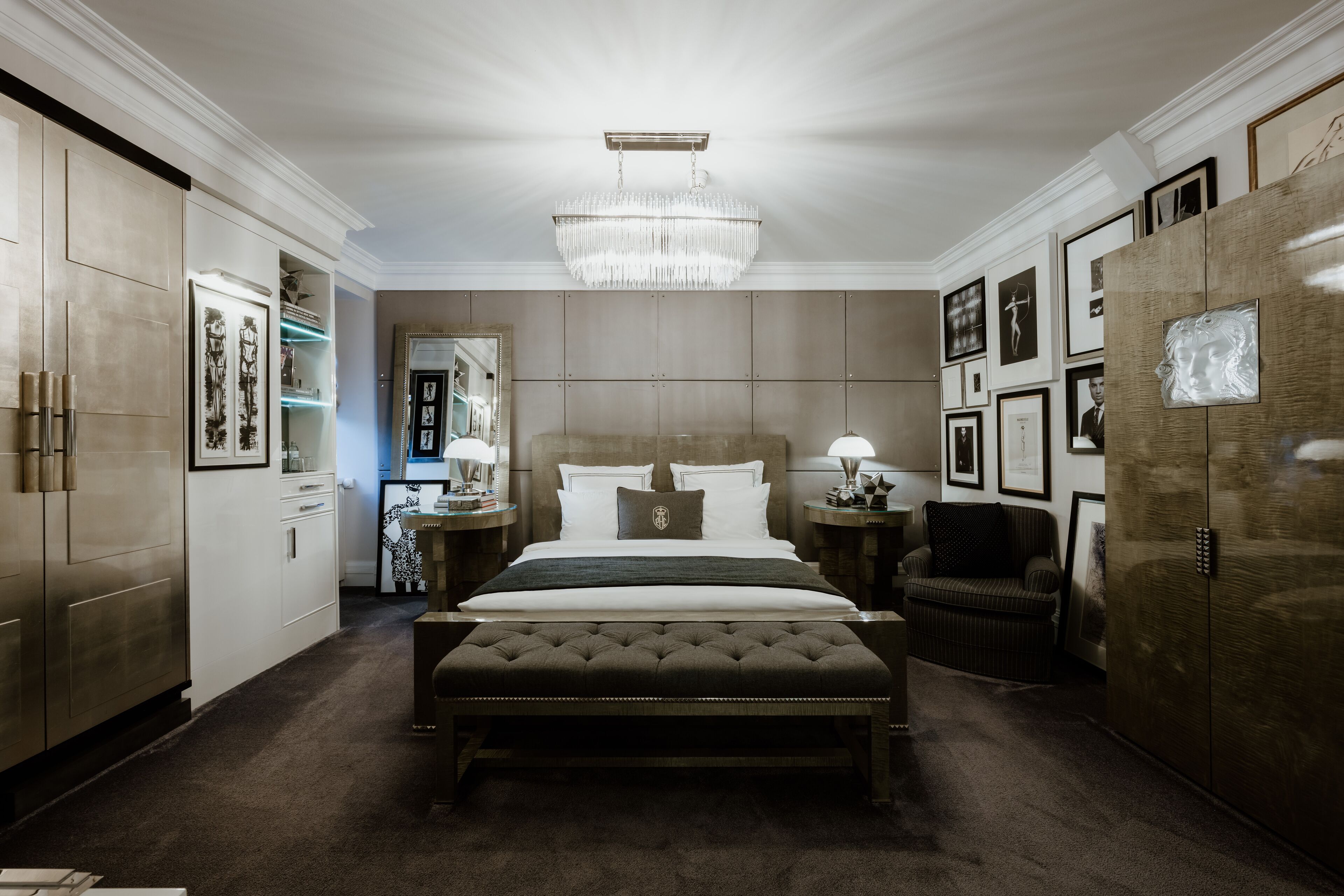 Ein Schlafzimmer mit einem großen Bett, einer Chandelüster und gerahmten Bildern an den Wänden.
