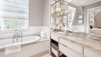 A modern bathroom with a freestanding bathtub, double sinks, and a large mirror.