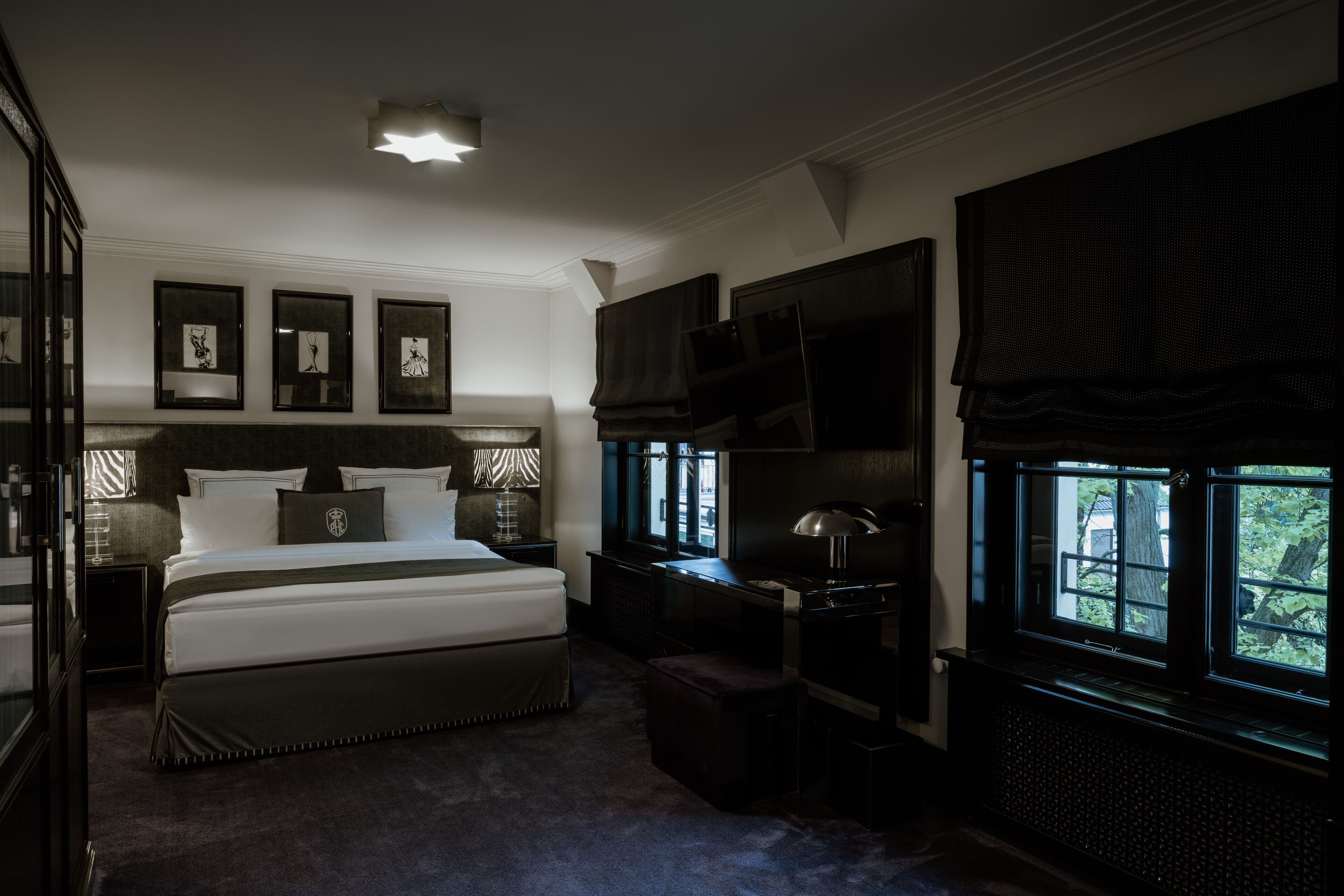 A bedroom with a large bed, a desk, and a window with a view of trees.