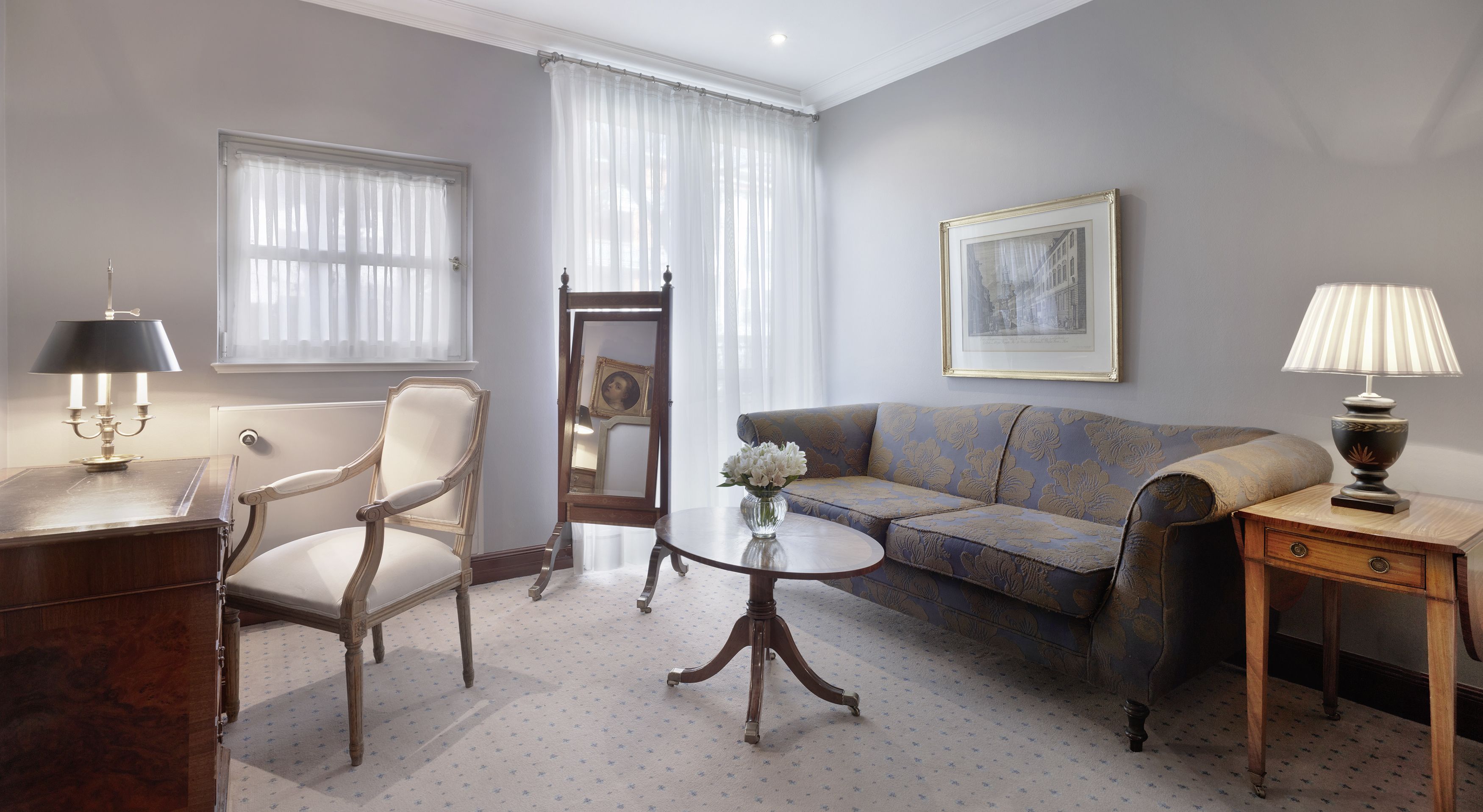 Una sala de estar con sofá, sillón, mesa de centro y lámpara.