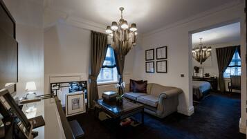 A hotel room with a sofa, a coffee table, a chandelier, and a bed.